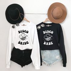 two t - shirts that say disco and babe hang on a wall next to hats