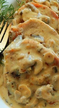 a white plate topped with meat and gravy next to a knife and fork