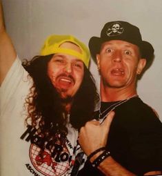 two men with long hair and hats posing for the camera