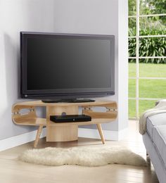 a flat screen tv sitting on top of a wooden stand in front of a window