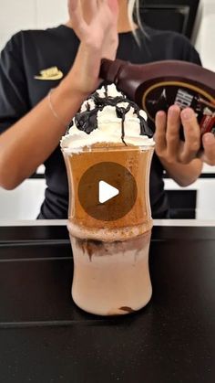 a woman holding up a cup with whipped cream and chocolate