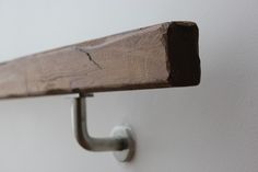 a close up of a metal hook on a wooden shelf with white walls in the background