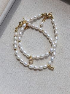 Create an elegant and unique look with our 26-letter Pearl Bracelet. Featuring individual letter charms and lustrous pearls, it adds a special touch to any outfit. Crafted with high-quality materials for lasting beauty and durability. Celebrate your individuality and add this one-of-a-kind piece to your jewelry collection! Metal: 18K Recycled Gold Plated On Brass Gemstone:Freshwater Pearl(3.5-4mm),Cubic Zirconia Pendant Length：7mm Chain Length: 170-195mm Weight: 4.3g Bracelets Pearl, Pearl Bracelets, Letter Charms, Letter Pendants, Recycled Gold, Pearl Bracelet, Chain Lengths, Chain Length, Freshwater Pearls