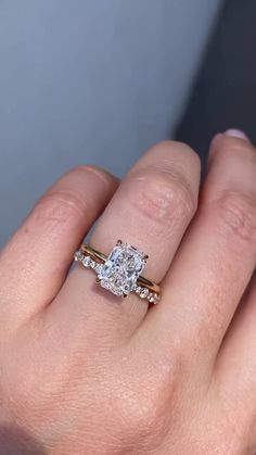 a woman's hand with a diamond ring on top of her finger and an engagement band