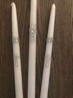 three white candles with cross decorations on them