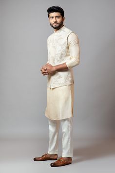 Off white bundi with jaal embroidered motifs and band collar. Paired with embroidered sleeve kurta and churidar.
Component: 3
Embroidered
Neckline: Band
Sleeve Length: Three quarter
Fabric: Bam Silk, Malai Cotton
Color: White
Side pockets
Closure: Concealed buttons - Aza Fashions Nehru Jacket For Men, Kalki Fashion, Kurta Set For Men, Embroidered Motifs, Nehru Jacket, Nehru Jackets, Embroidered Neckline, Band Collar, Churidar