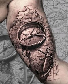 a man's arm with an anchor, compass and map tattoo on the forearm