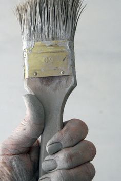 a close up of a person holding a paintbrush in their hand with the brush pointed to the side