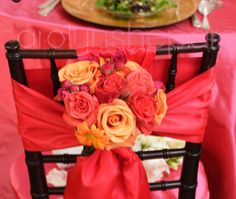 a red chair with flowers on it next to a pink table cloth and silverware