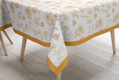 the table cloth is yellow and white with gold designs on it, along with two wooden legs