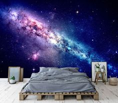 an image of a bedroom with a large galaxy wall mural on the wall and wooden flooring