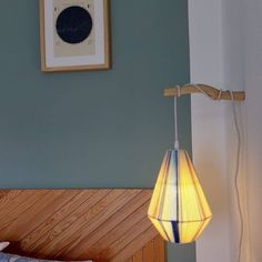 a lamp that is sitting on the side of a bed next to a framed picture