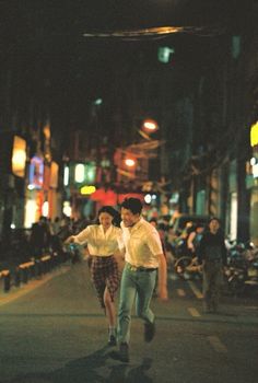 two people are walking down the street at night