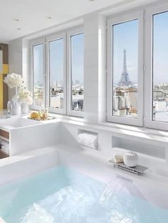 a bathroom with a large jacuzzi tub next to two windows overlooking the eiffel tower