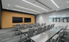 an empty conference room with gray chairs and a flat screen tv on the wall in front of it