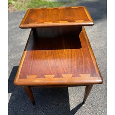 two wooden tables sitting on top of each other in the middle of a street with grass behind them