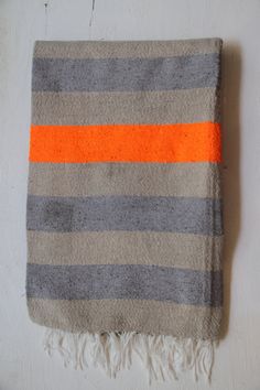 an orange and grey striped blanket laying on top of a white wall