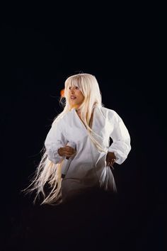 a woman with long blonde hair standing in the dark