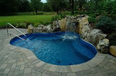 a swimming pool surrounded by rocks and water features a waterfall