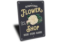 a sign that says downtown flower shop with a white rose in the center and green leaves on it