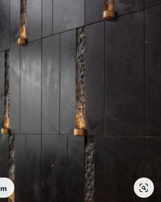 a black wall with some gold lights on it's sides and the bottom half