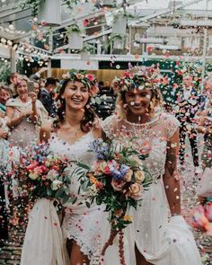 two brides are surrounded by confetti as they walk down the aisle