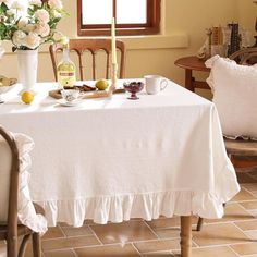 a table with two chairs and a white table cloth on it in front of a window