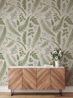 a wooden cabinet sitting in front of a wall with green leaves and flowers on it