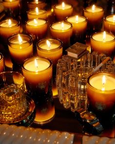 many lit candles sitting on top of a table next to a glass container with a candle in it