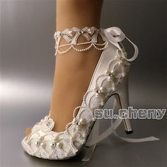 a woman's white high heeled wedding shoes with pearls and ribbons on the ankle