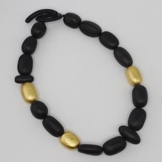 Discover the exquisite craftsmanship of our Handcrafted Ebony Wood Bead Necklace from Mali, adorned with luxurious 24K gold leaf accents. Each bead is meticulously crafted from high-quality ebony wood, showcasing its rich, natural beauty. The addition of gold leaf accents adds a touch of opulence, making this necklace a standout piece. Lightweight and comfortable, it’s perfect for all-day wear. This necklace is a versatile accessory, ideal for adding a touch of sustainable elegance to any outfit Wood Bead Necklace, Ebony Wood, Pendant Rings, Beauty Collection, Bead Necklace, Wood Beads, Ring Necklace, Gold Leaf, Necklaces Bracelets