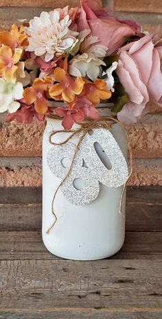 a white mason jar filled with flowers on top of a wooden table