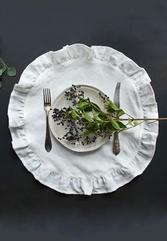 a white plate topped with green leaves next to a fork and knife on top of a table