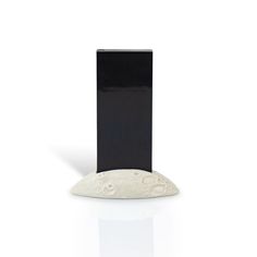 a black and white vase sitting on top of a table next to a square object