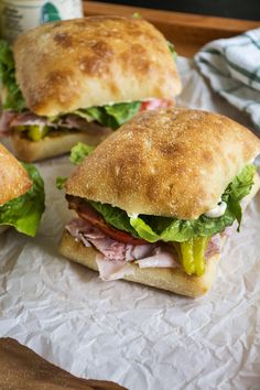 three sandwiches sitting on top of a piece of wax paper