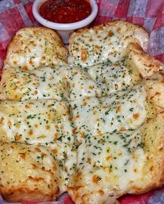 a pizza with cheese and sauce on it sitting on top of a red checkered paper