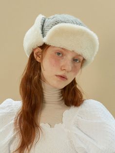 a woman with red hair wearing a white sweater and a fur hat on her head