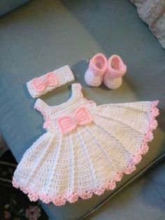 a crocheted baby dress and booties sitting on top of a couch