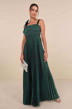 a woman wearing a green pleaed dress with one shoulder and an asymmetrical neckline