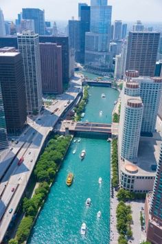 an aerial view of boats on the water in a canal near tall buildings and skyscrapers