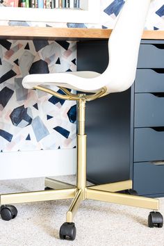 a white office chair sitting in front of a desk with bookshelves and drawers