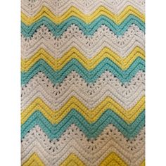 a crocheted blanket with yellow, blue and white waves on the bottom is shown