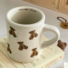 a coffee mug with teddy bears on it sitting on top of a stack of books