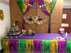 a mardi gras table with purple and green decorations