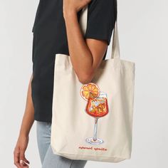 a woman carrying a tote bag with an image of a drink and orange slices on it