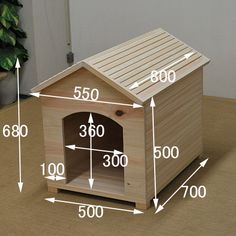 a wooden dog house with measurements for the top and bottom half, on a table