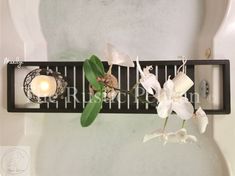 a bath tub filled with white flowers and candles next to a wall mounted soap dispenser