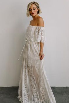 a woman wearing a white lace dress with off the shoulder sleeves and an open back