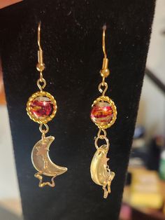 Stunning golden solar system inspired earrings, with glass beads, acrylic moons, and some metal moons. The gold ring rotates around the "planet" bead making for an out of this world pair of earrings! Nickel-free Adjustable Space-themed Jewelry, Celestial Metal Earrings With Sun And Moon Design, Handmade Celestial Metal Earrings, Handmade Metal Celestial Earrings, Celestial Sun And Moon Metal Earrings, Handmade Space-themed Dangle Jewelry, Celestial Nickel-free Adjustable Earrings, Celestial Nickel-free Earrings, Adjustable Celestial Nickel-free Earrings