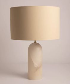 a white table lamp with a beige shade on it